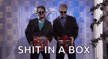 two men in suits and sunglasses are holding gifts and the words shit in a box are above them .