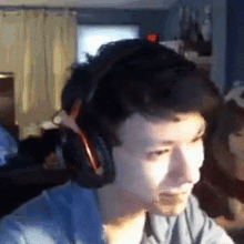 a man wearing headphones is sitting at a desk in a living room .