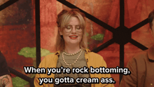 a woman wearing glasses and a pearl necklace says when you 're rock bottoming you gotta cream ass
