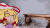 a stuffed doll with yellow eyes sits next to a small wooden bench