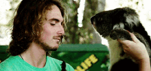 a man in a green shirt is holding a small koala bear
