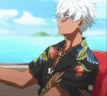 a man in a hawaiian shirt is sitting on a boat looking out at the ocean .