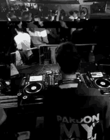 a dj is sitting at a table in front of a crowd at a party .