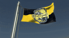 a yellow and black flag with a crest that says hufflepuff