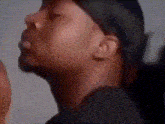 a close up of a man 's face wearing a hat and a black shirt .