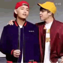 two young men are standing next to each other and one of them is wearing a red hat .