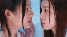two women are looking at each other 's faces and touching their lips