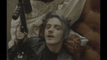 a man is laying on a bed holding a gun