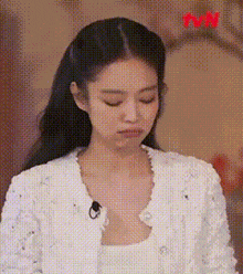 a close up of a woman wearing a white jacket and a white tank top .