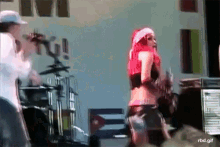 a woman with red hair and a santa hat is dancing on a stage while a man plays a guitar
