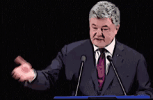 a man in a suit and tie stands at a podium giving a speech