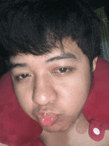 a man with a red pillow around his neck is making a face