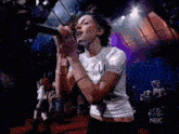 a woman is singing into a microphone on stage in front of a crowd .