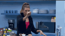 a woman is standing in a kitchen with a microwave and plates on the shelves