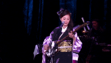 a woman singing into a microphone while holding a musical instrument