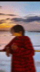 a blurry picture of a person standing on a balcony looking out over the ocean at sunset .