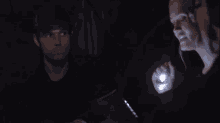 a woman is holding a flashlight and talking to a man in the dark