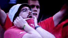 a man wearing a hat and a red shirt with the puma logo on it