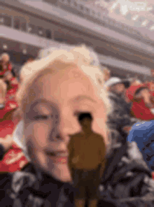 a young boy is taking a picture of himself in a stadium with a man standing in the background .