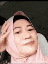 a woman wearing a pink hijab and a silver ring is making a funny face