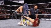 two women are wrestling in a wrestling ring with a referee