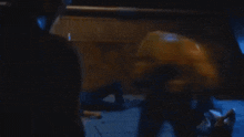 a person is laying on the floor in a dark room while another person stands behind them .
