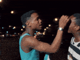 a man in a blue tank top touches another man 's forehead