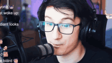 a man wearing glasses and headphones talking into a microphone