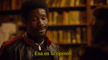a man in a leather jacket says " esa es tu opinion " in front of a bookshelf