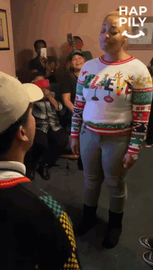 a woman wearing an ugly christmas sweater stands in front of a crowd