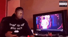 a man wearing a shirt that says #fuck system looks at a computer screen