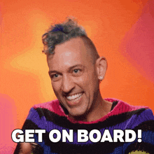 a man in a striped sweater is smiling and says " get on board "