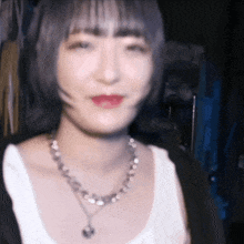 a woman wearing a white tank top and a silver necklace