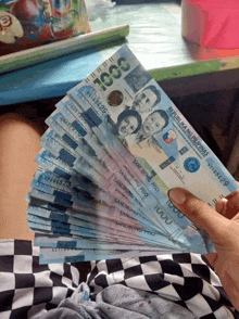 a person is holding a stack of 1000 pesos