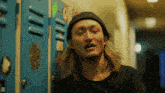 a man leaning against a blue locker with a sticker on it that says ' d '