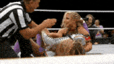 a referee is standing next to a wrestler in a ring .