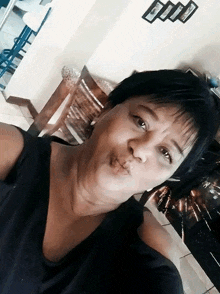 a woman blowing a kiss while taking a selfie in a room