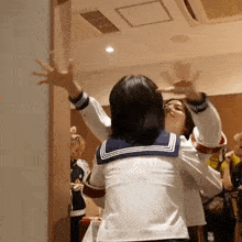 a girl in a sailor 's uniform is standing in a room with her arms outstretched .