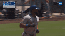 a baseball player is running on the field with a scoreboard behind him