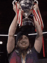 a man holds up a trophy with ribbons around it