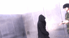 a gif from gifrun.com shows a man in a black hooded jacket talking to another man