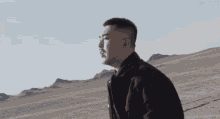 a man in a black jacket is standing in a desert