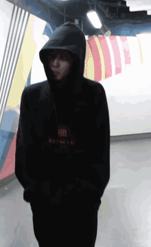 a man wearing a black balenciaga hoodie stands in a dark room