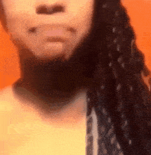 a close up of a woman 's face with braids and a piercing in her mouth .