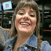 a woman wearing a denim jacket is smiling for the camera