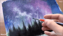 a person is painting the aurora borealis with a brush on a piece of paper
