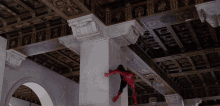a man in a spiderman costume is hanging from a ceiling