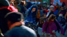 a woman in a blue dress is dancing in a crowd of people on a street .