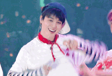 a young man wearing a blue hat and a red scarf smiles for the camera