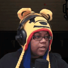 a woman wearing headphones and a winnie the pooh hat talks into a microphone